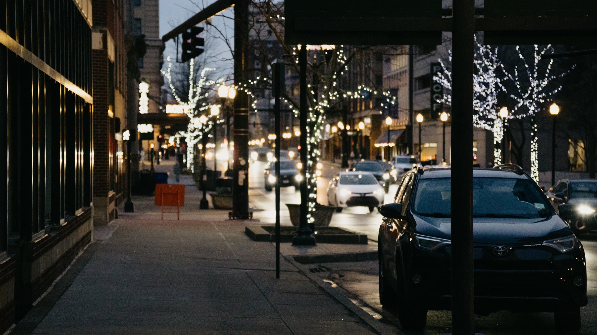 Downtown Lexington street at dusk with lit trees and headlights